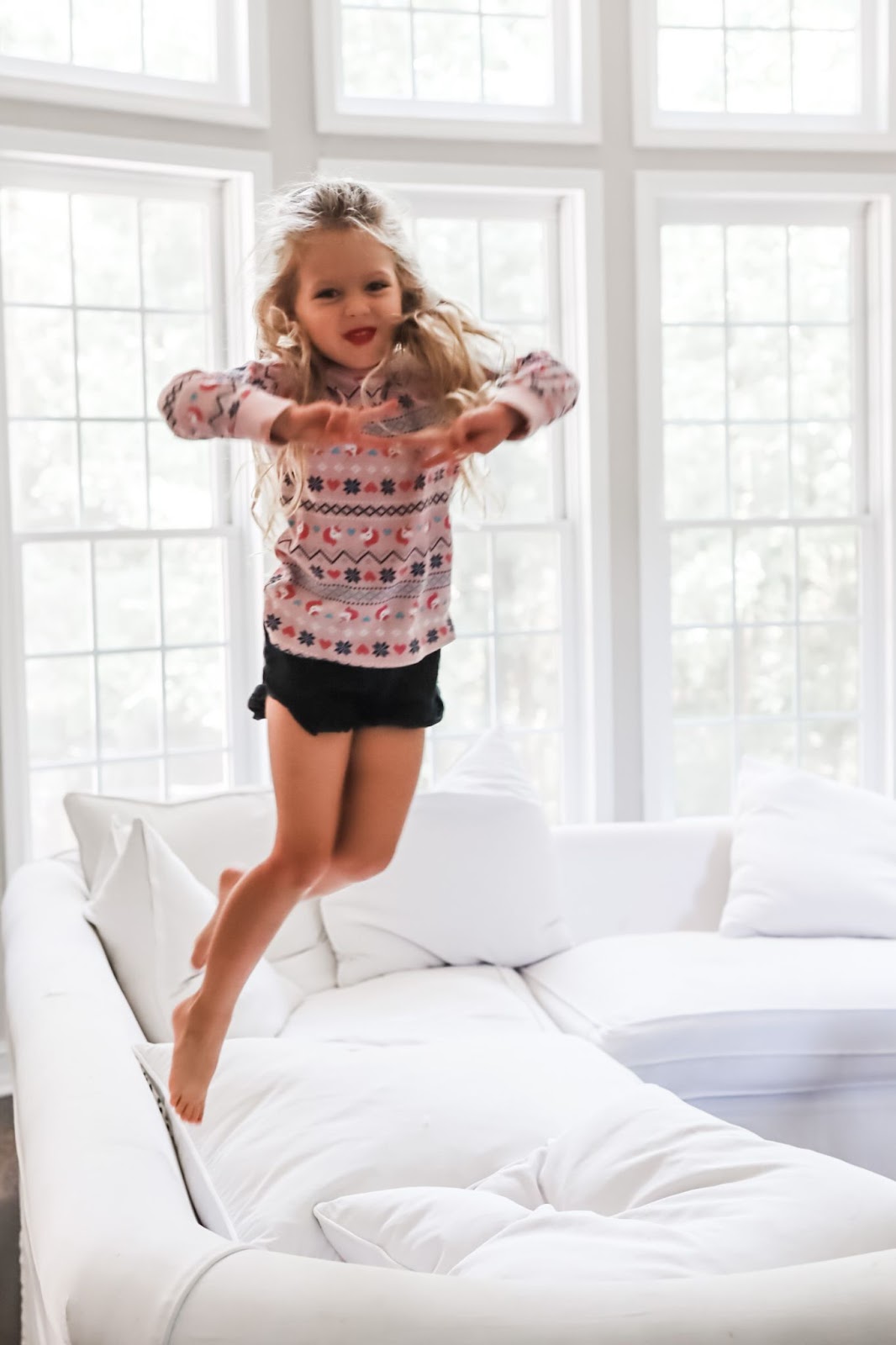 Medicine Cabinet Ideas by popular Atlanta lifestyle blog, City Peach: image of a little girl jumping on a white sectional couch.
