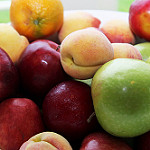 close-up of a bowl of fresh fruit, including apples, oranges, and peaches