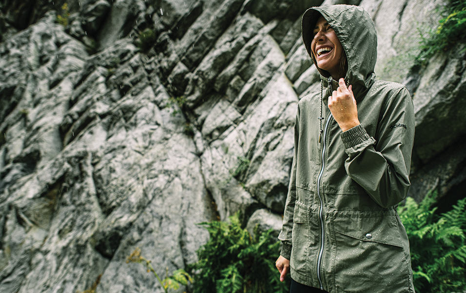 Woman laughing near a rock wall. 