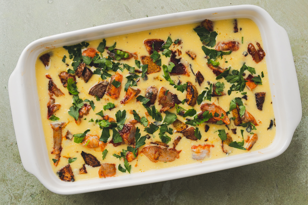 egg mixture with shrimp, potatoes and parsely in a baking dish