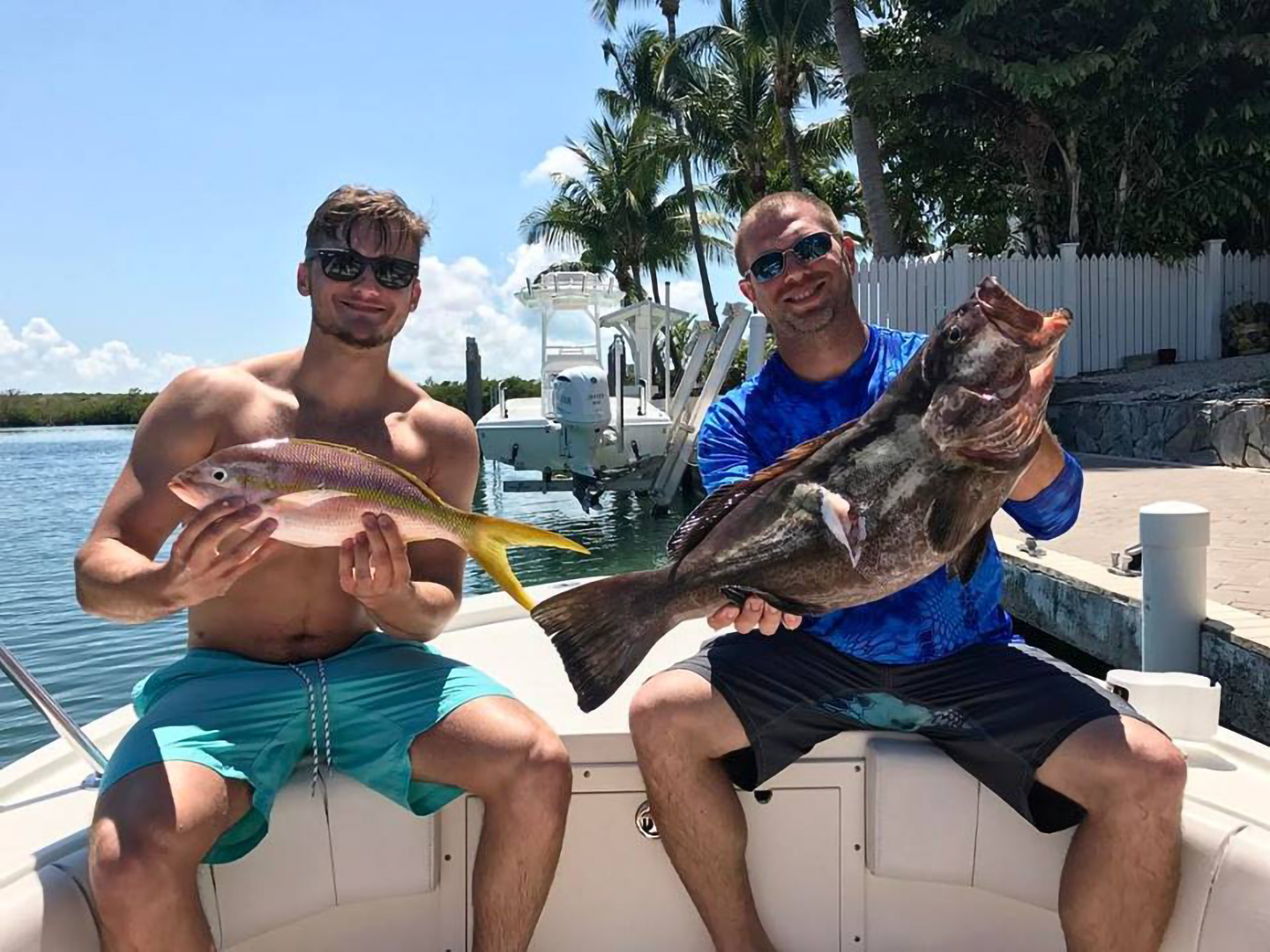Two anglers with a Grouper and Yellowtail Snapper sitting on the bow of a boat, dockside in the Florida Keys