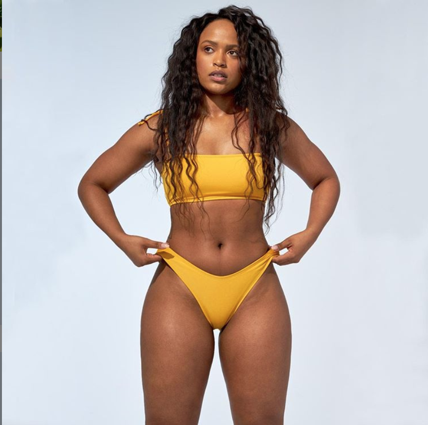 A person in a yellow dress posing for the cameraDescription automatically generated