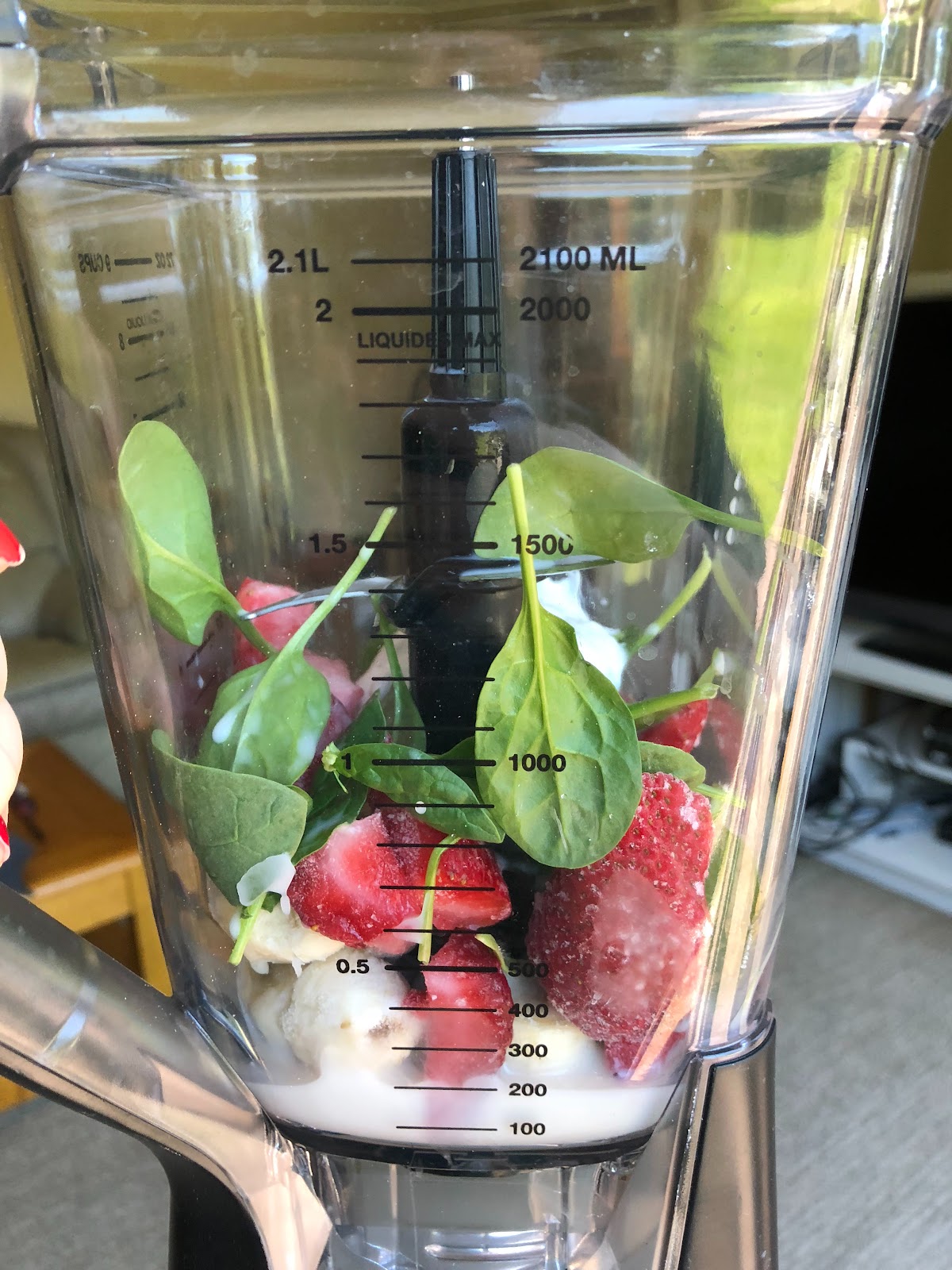 Frozen banana and strawberries in the blender with spinach, almond milk, greek yogurt and blueberries.