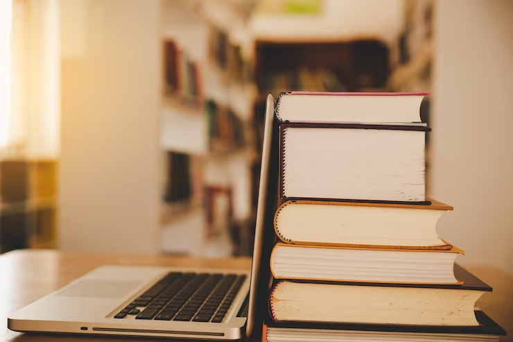 A laptop and a stack of books symbolize digital education. Relevant to the blog MCAT Truths Revealed: Debunking Popular Myths.