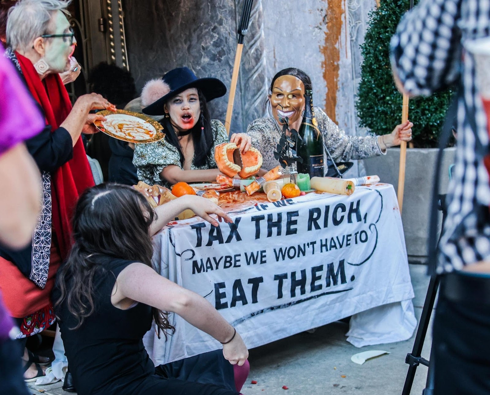 Halloween costumed rebels eat round a table outside an appartment block entrance