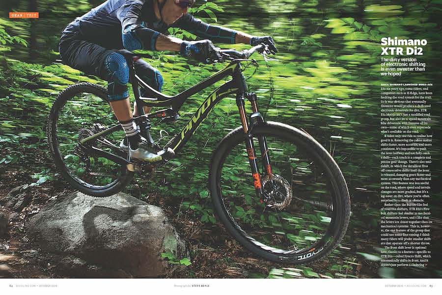 Tearsheet of a downhill trail cyclist making a jump over a rock in a forest. The image is overlayed with information about the bike's electronic gears.