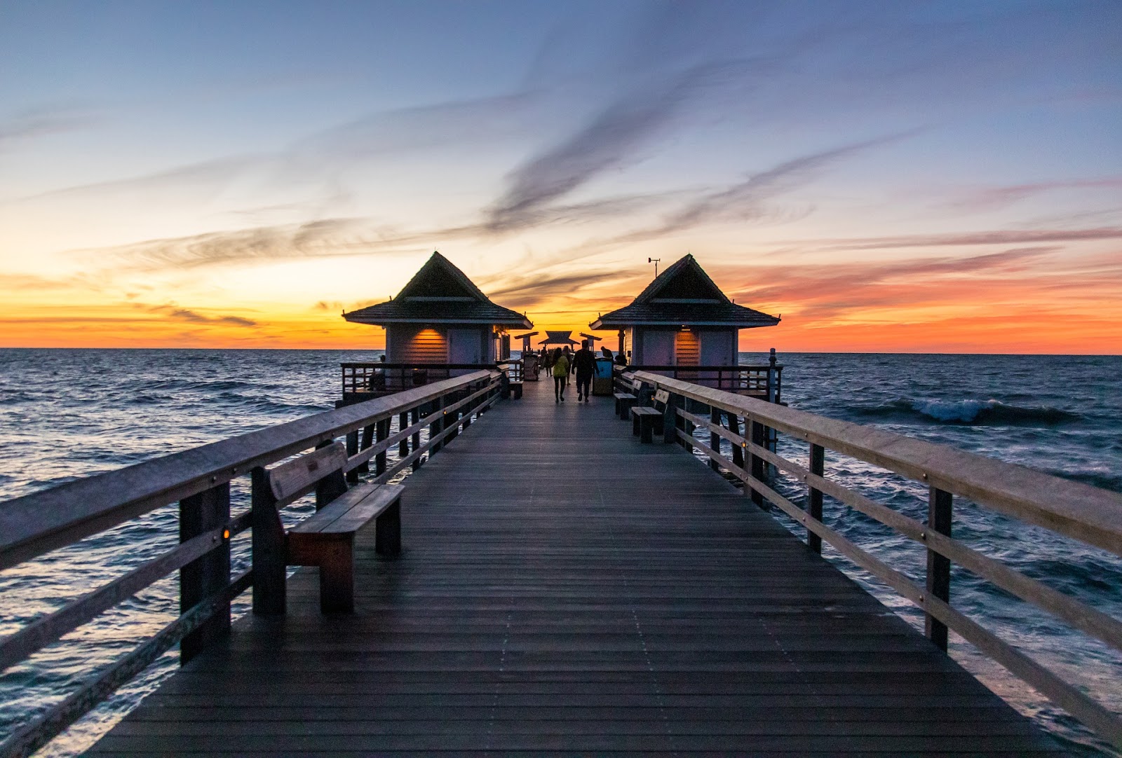 wooden pier atop blue wavy ocean during sunset in naples florida