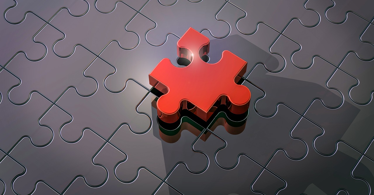 Un puzzle composé de pièces blanches grises à l'exception d'une pièce rouge vif.