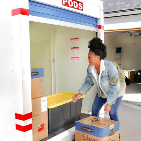 A woman loads boxes into a PODS container