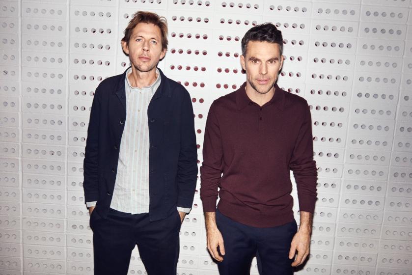 Two men standing in front of a white wall

Description automatically generated with medium confidence