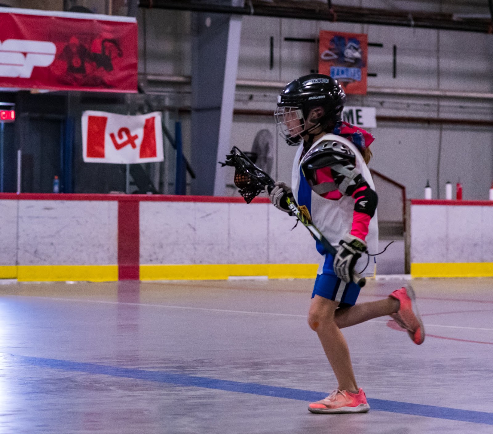 Girl cradling lacrosse ball, running up the floor