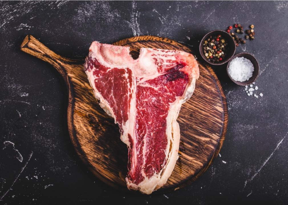 Raw marbled steak on a wooden serving board.