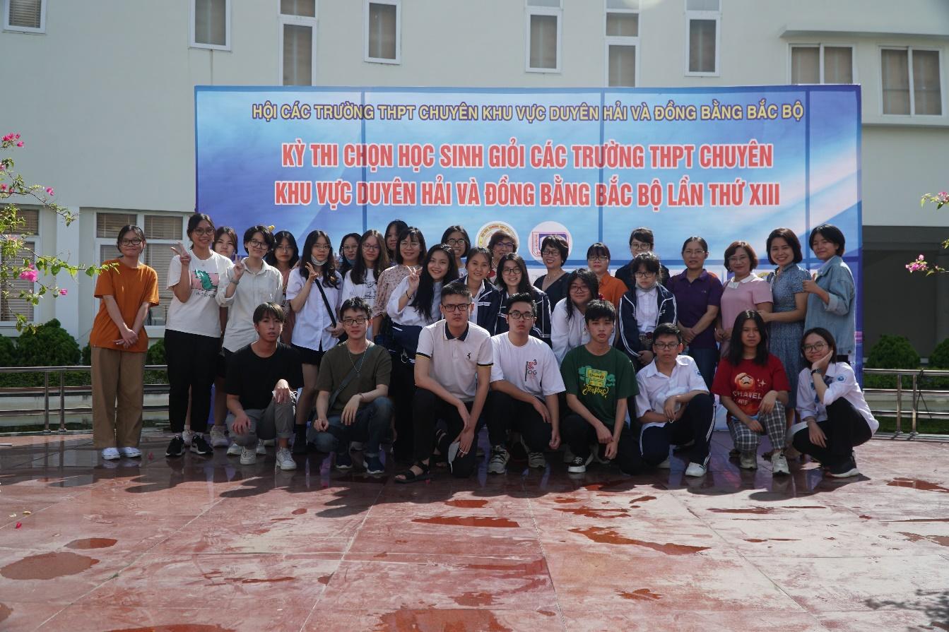 A group of people posing for a photo in front of a sign</p>
<p>Description automatically generated