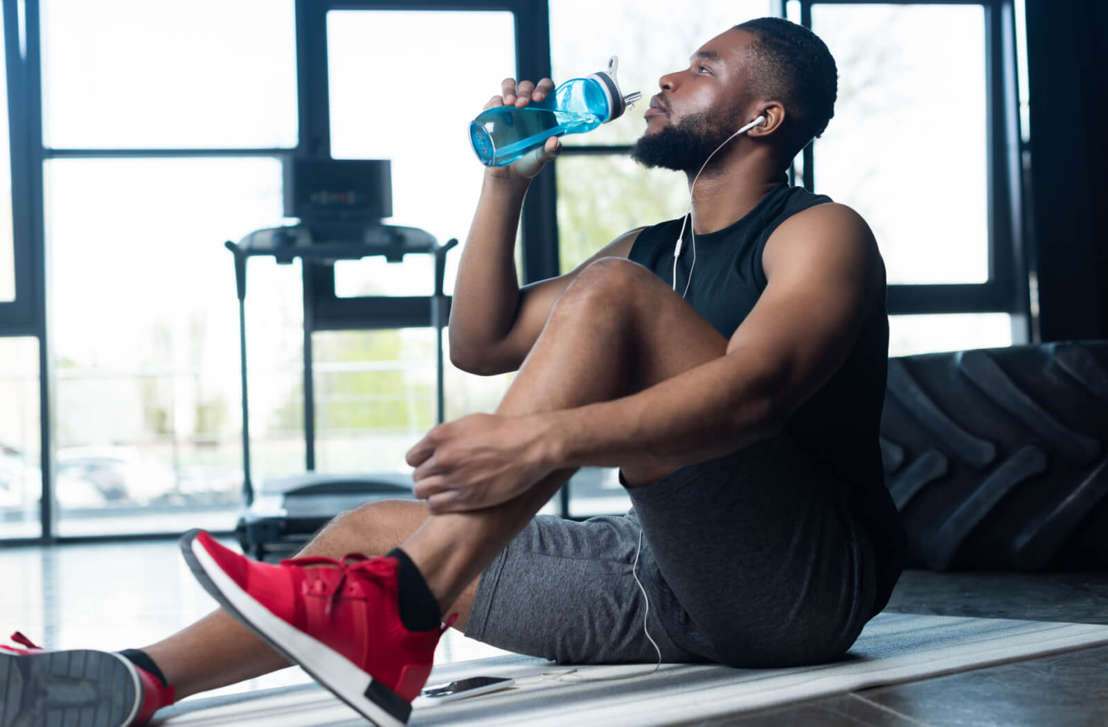 An athletic man in his sportswear drinking water from his reusable water bottle.