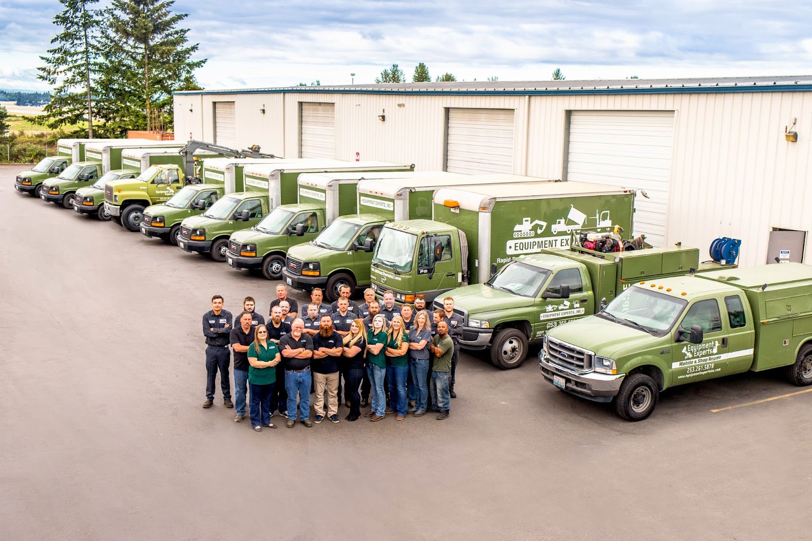 An aerial photo of a fleet team crossing their arms with their arsenal of fleet trucks in the background