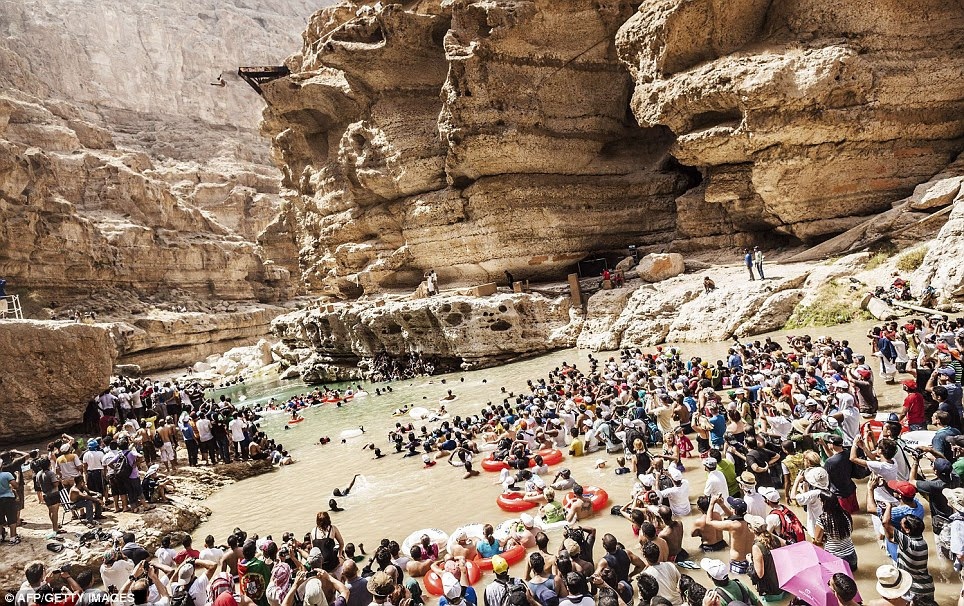 Take aim! Crowds watch in fascination as the competitors scale the cliff before jumping off and making a big splash
