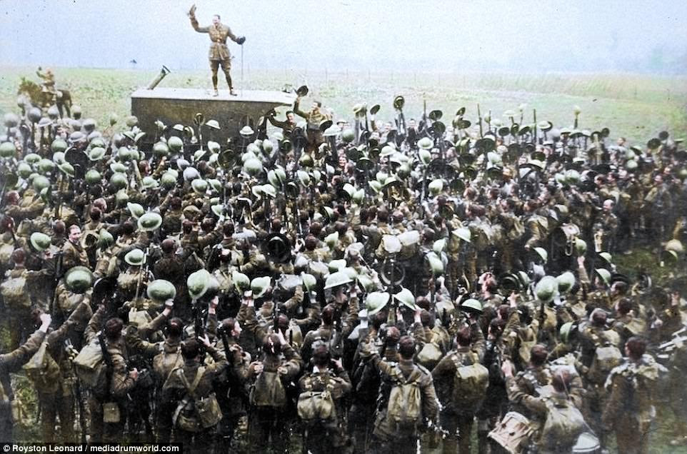 Stirring: Photos from the end of First World War have been brought to life in colour to coincide with the 99th Armistice Day. Pictured: A crowd of soldiers on the Western Front celebrating as an officer announces the news of the Armistice