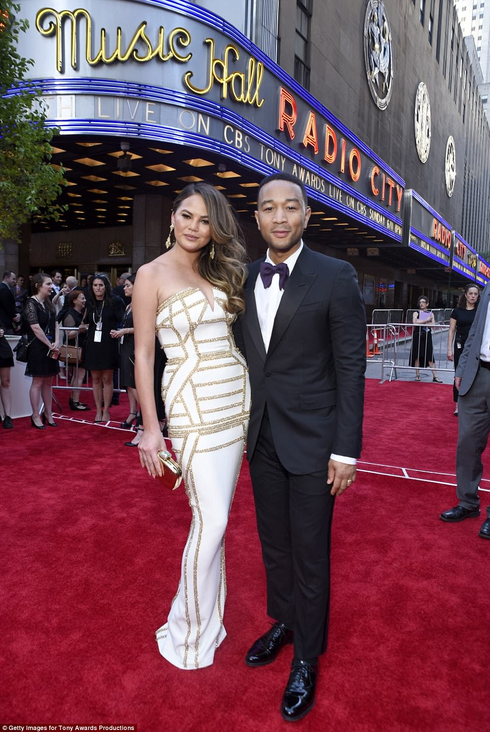 Focada: Chrissy, que piscou um pingo de clivagem, terminou a curva de seu vestido com uma mini-embraiagem; Retratado com John