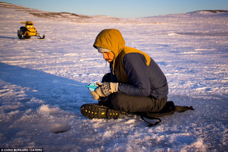 Holed up: Alek Parker takes a rest from hitting the waves. In California he would probably lay on the golden sands, here he tries a spot of ice fishing 