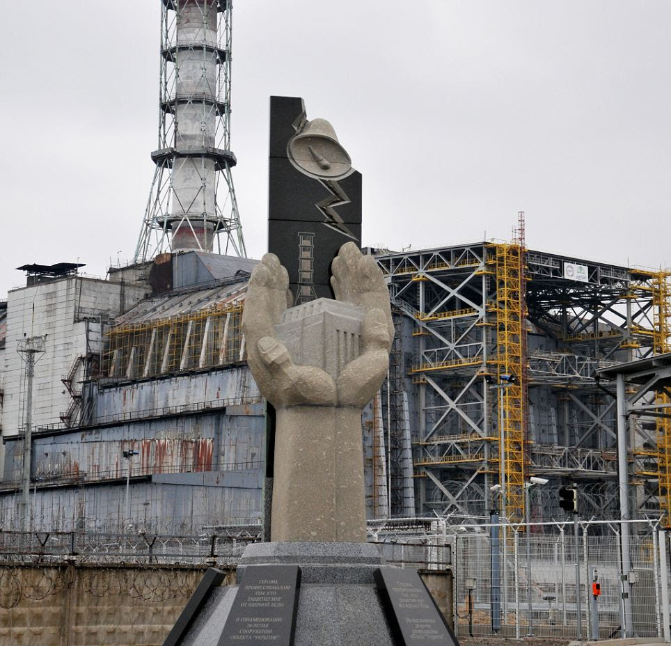 A memorial to the victims of the Chernobyl disaster in front of wrecked power station