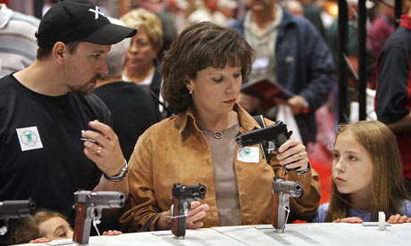 A family compare handguns at a National Rifle Association meeting 