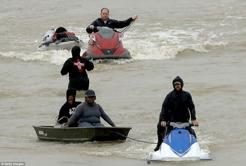 Men use jet skies to rescue stranded residents in Houston and tow them to safety as the flooding from Harvey continues