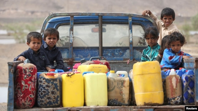 Children ride on the back of a truck loaded with water jerrycans at a camp for internally displaced people in the Dhanah area of the central province of Marib, Yemen, April 30, 2016.