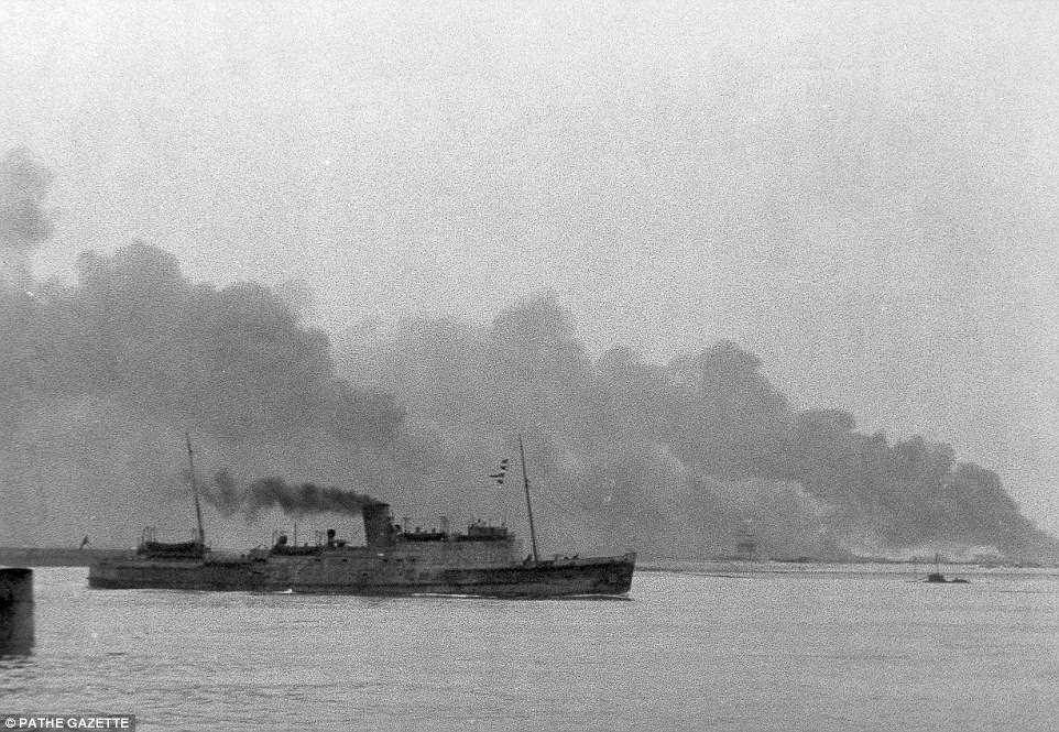 A ship with decks crammed full of soldiers - many of them only carrying rifles - sets off home for Britain as Dunkirk burns in the background