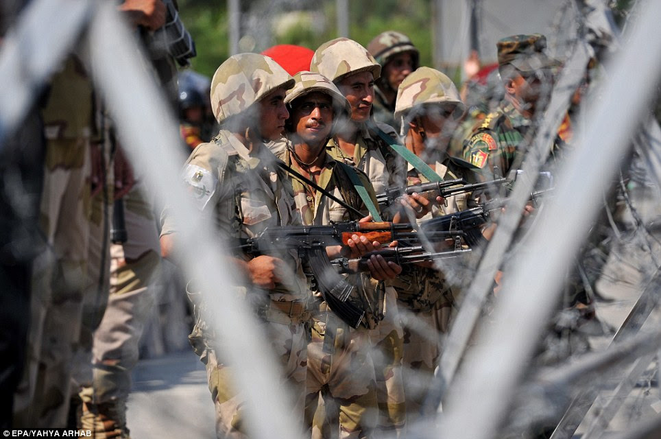 Egyptian Republican Guards forces stand guard behind barbed wire outside the headquarters of the Republican Guard. At least six have been killed