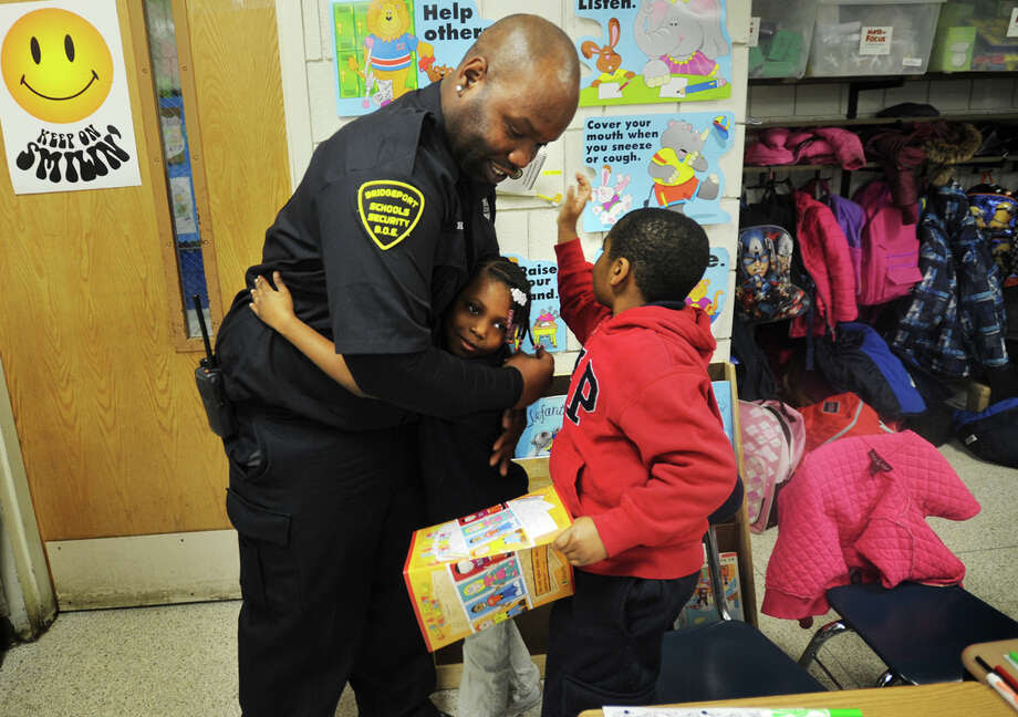 Curiale School security guard Harry Bell receives hugs from second graders Tatyana Garner and Mario Shady, both 7, after passing out copies of his coloring book, "Color a Positive Thought", at the school on Tuesday, November 25, 2014. Photo: Brian A. Pounds / Connecticut Post