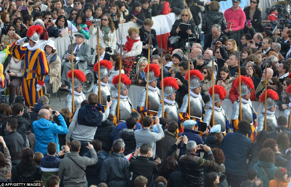 Arrival: Swiss guards make their way through the crowds at St Peter's Square 