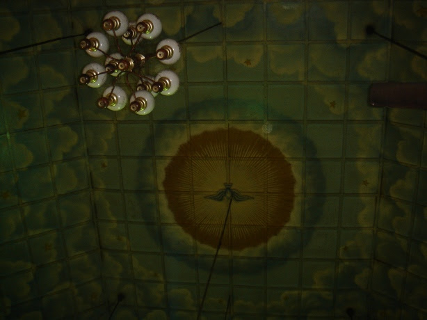 old chandelier hangs from the mural adorned ceiling in kadamattom church