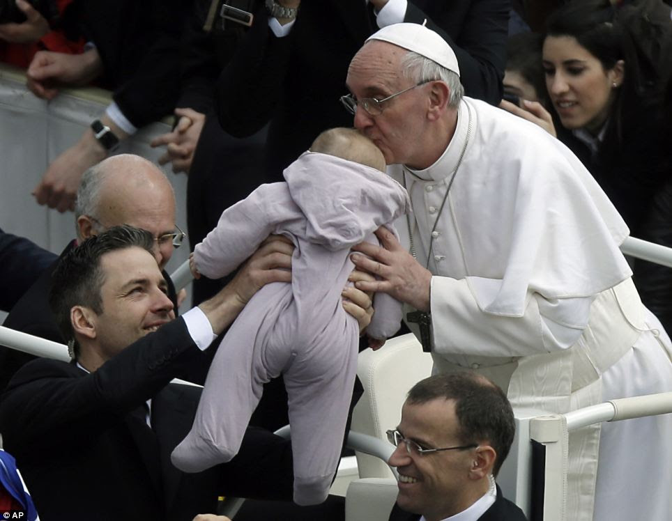 Kiss: Pope Francis kisses a baby after celebrating his first Easter Mass in St Peter's Square