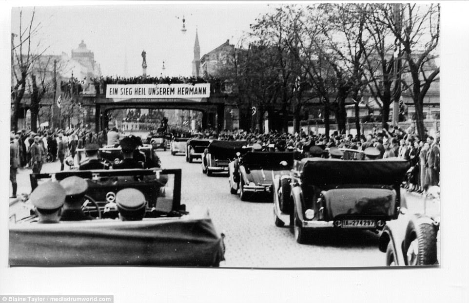 To celebrate the Third Reich's bloodless reoccupation of the former German Rhineland, Goering embarked on a combined automobile Rhine River cruise on 17 March 1936. Here just under the overhead banner that reads 'A victory hail for Our Hermann' he stands at center in the lead vehicle of the motorcade of at least a dozen cars