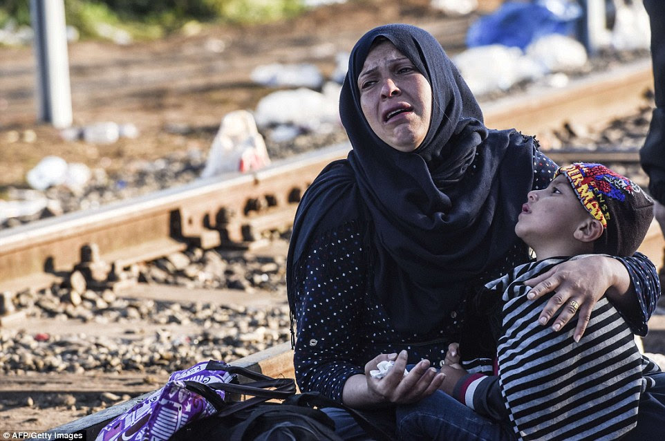 A refugee breaks down in tears as she cradles a child be the side of railway tracks at the Hungary-Serbia border near the town of Horgos. Thousands are expected to cross the border today