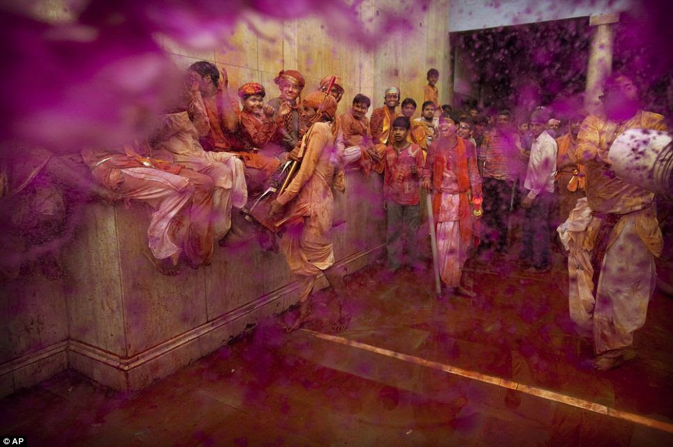 Burst of colour: A Hindu worshipper throws a bucket of colored water on others during Lathmar Holi at Nandagram Temple in Nandgaon yesterday