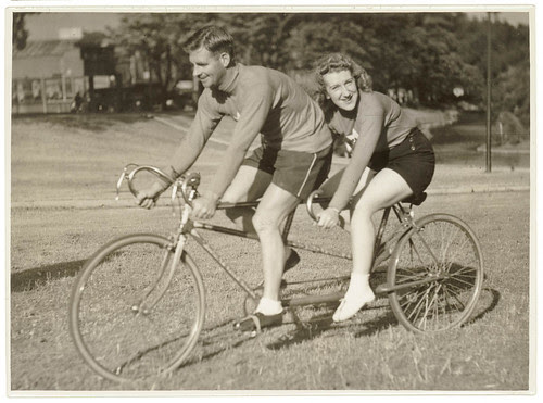 Oppy (Hubert Opperman) and woman, possibly Edna Sayers, on tandem bicycle, by Sam Hood