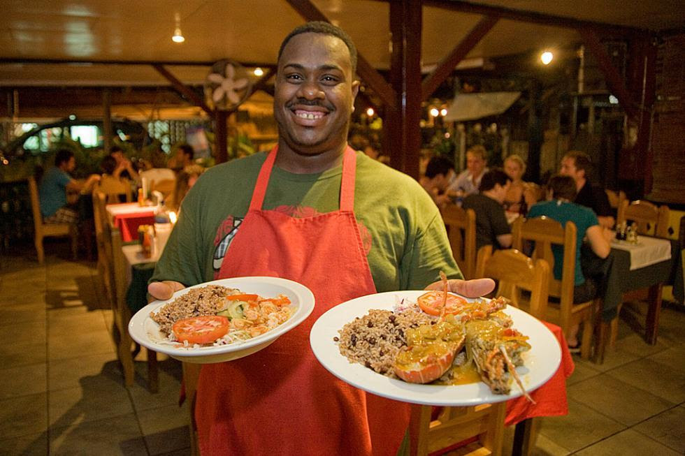 Afro-Caribbean Culture on Costa Rica’s Caribbean Coast
By Dan Tucker
Costa Rica is the most homogeneous nation in Central America, but its Afro-Caribbean minority — numbering about 40,000, concentrated in the Caribbean coastal province of Puerto Limón — brings calypso, reggae, spicy cuisine, and a kicking Carnaval into the mix of Tico culture.
The Banana’s Legacy
Small numbers of enslaved Africans were brought into the country in the 16th century by large estate owners to cultivate cacao; it wasn’t until the 19th century that freed Jamaican slaves were imported in significant numbers by Minor Keith to build the Atlantic Railroad, harvest coffee, and almost as an afterthought, grow bananas for what was to become the United Fruit Company. (Bananas were initially grown to feed the workers. The enormous surpluses became an exotic and luxurious hit when exported to the United States, Europe, and elsewhere.)
Due to their geographical isolation in Puerto Limón, and the fact that they are generally Englishspeaking Protestants, Afro–Costa Ricans have retained their unique cultural identity to this day, adding a distinct reggae lilt to an otherwise Latin culture.
Cool Characters, Hot Food
If Costa Rican cuisine is fresh and tasty but relatively undistinguished, Afro–Costa Rican food is the remedy for those craving stronger flavors. Many dishes are composed of yam, cassava, plantain, sweet potatoes, cocoyam, coconut, lentils, rice, fish, meat, and other readily available ingredients.
Salted codfish and akee (a lychee-like fruit, only part of which is edible), jerk chicken, stewed goat, fried breadfruit, and rice and beans cooked in coconut milk or spiked with scotch bonnet or habanero peppers — a far cry from the usual gallo pinto — are West Indian specialties that are widely enjoyed in Puerto Limón. All are readily available on the streets of Limón during Carnaval
Carnaval
There is no better place to immerse yourself in Afro–Costa Rican music and culture than Limón during Carnaval, a fantastical, riotous, cacophony of parades, concerts, street food, and carnival rides. Celebrated annually for several days around the weekend closest to October 12, Limón’s Carnaval parades feature floats and comparsas, community-organized marching bands with teams of dancers in elaborate costumes. Performing precisely choreographed routines, the wildly costumed comparsas compete for prizes.
Carnival in Costa Rica, a 1947 musical confection starring Cesar Romero and Celeste Holm, offers a predictably cheesy and hilarious take on the festival.
Photo Caption: The delicious cuisine of the Soda Tamara restaurant in Puerto Viejo, Costa Rica. Photo by Adrian Hepworth