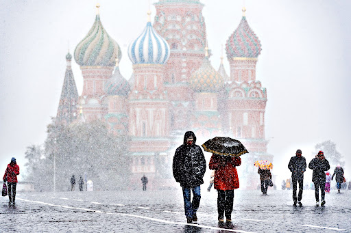 People walk across Red Square during a snowfall in Moscow on October 9,