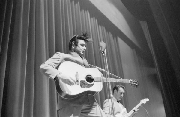 Johnny Cash Johnny Cash and electric guitarist Luther Perkins perform on stage in White Plains, New York. Cash's hair flies up in the air crazily as he jams to the music, ca. 1959.