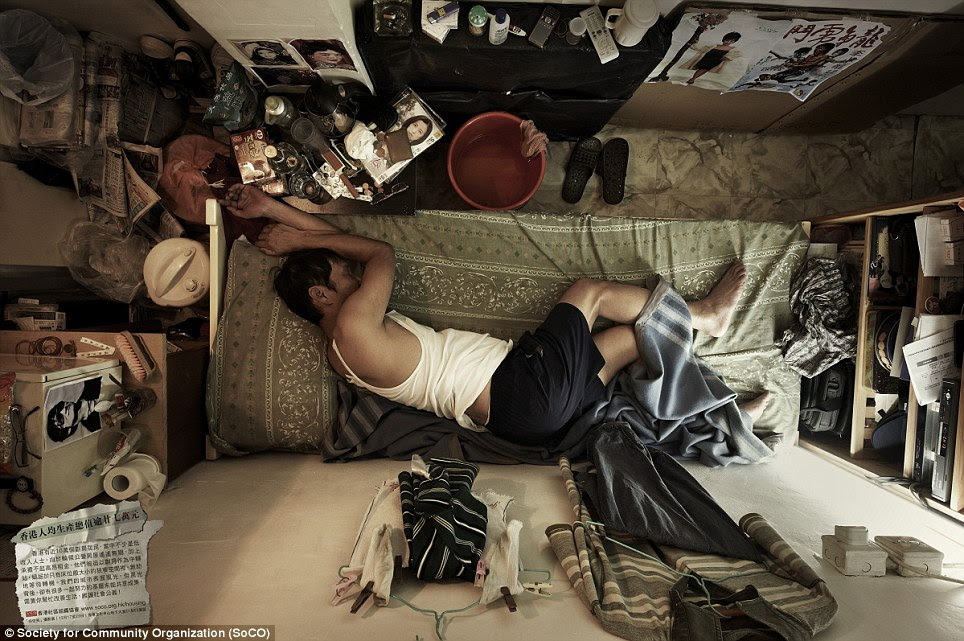 Hemmed in: A man takes a nap on his bed which fills most of the tiny 4ft x 7ft room. These bird's-eye images have been taken by a social group documenting the plight of the Hong Kong's most underprivileged people