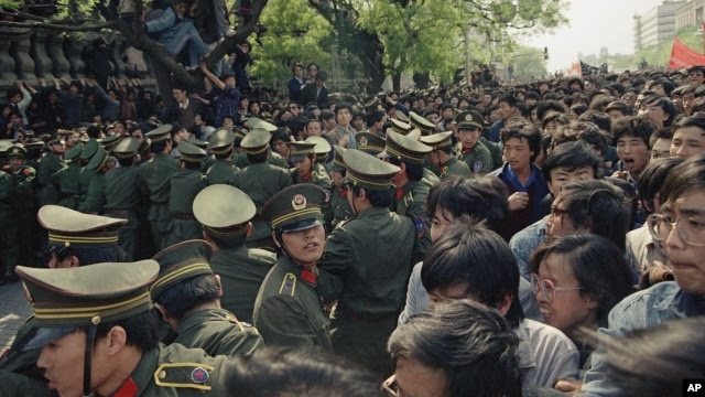 FILE - Students demonstrators scuffle with police as they try to break the guard line to march to the Tiananmen Square in Beijing, April 27, 1989.