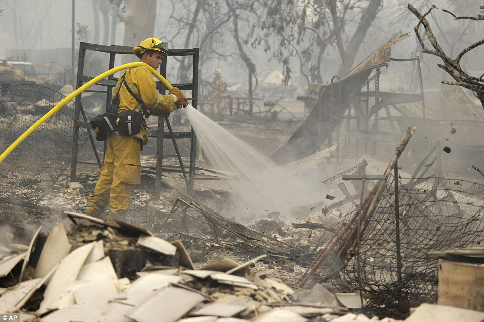 A firefighter with the Montezuma Fire District puts out hot spots on the remains of a home destroyed by the Valley Fire 