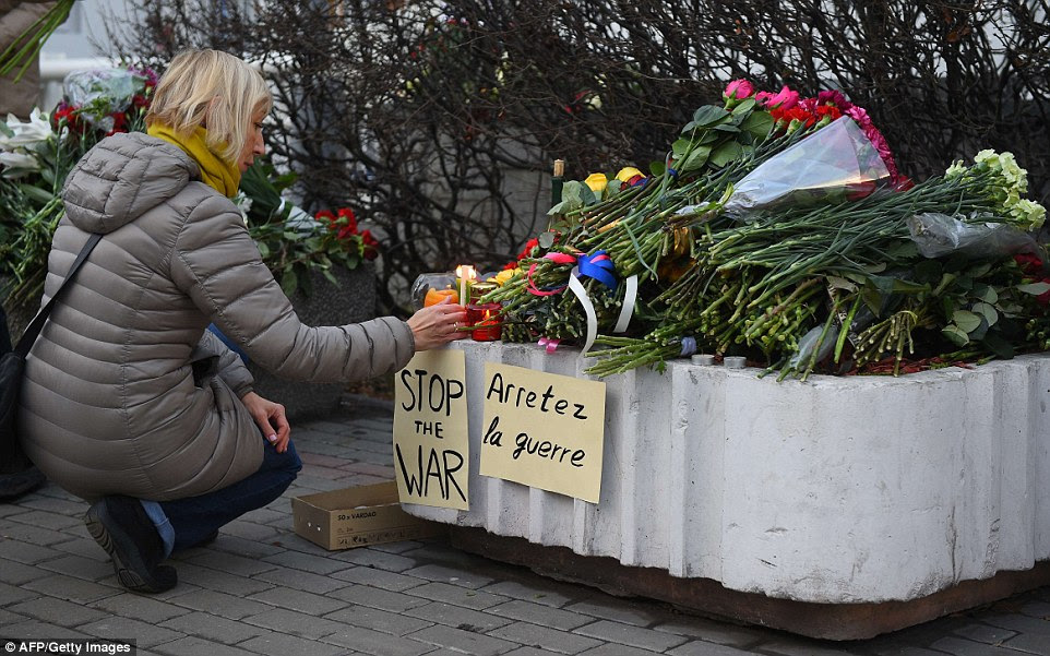 A woman places a lit candle outside the French embassy in Moscow this morning to pay tribute to the victims of the deadly attacks in Paris