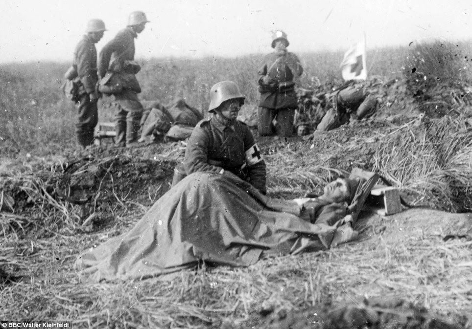 Final moments: Walter was just 16 when he fought at the Somme but his photos soon took on dark tone. Here he captures a German army medic kneeling beside a dying colleague - but he can do no more than offer comfort