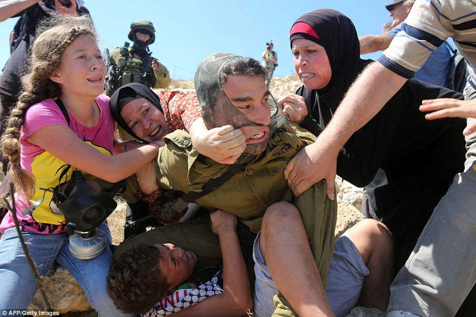 Attacked: As he pins the boy to a rock, the soldier finds himself ambushed by a girl, who forces the weapon from his grasp, and two women