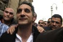 Bassem Youssef, the country's best-known satirist, gestures to journalists and activists as he arrives at the high court to appear at the prosecutor's office in Cairo