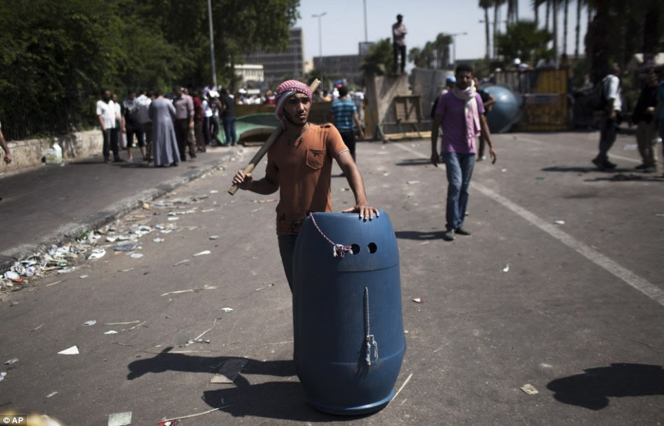 Armed: A Morsi supporter stands on guard holding a stick and a home-made shield prepared for clashes with police