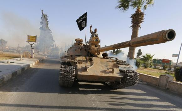 Militant Islamist fighters on a tank take part in a military parade along the streets of northern Raqqa province