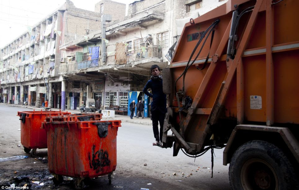 Clean up: A young man collects trash in central Baghdad. Some areas of the city are still said to be lacking services